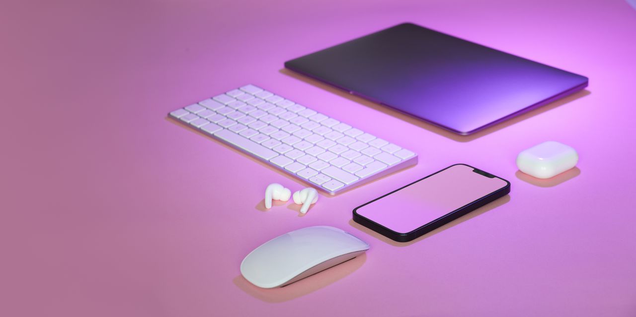 Flat lay of wireless tech gadgets on pink surface, highlighting modern electronics.