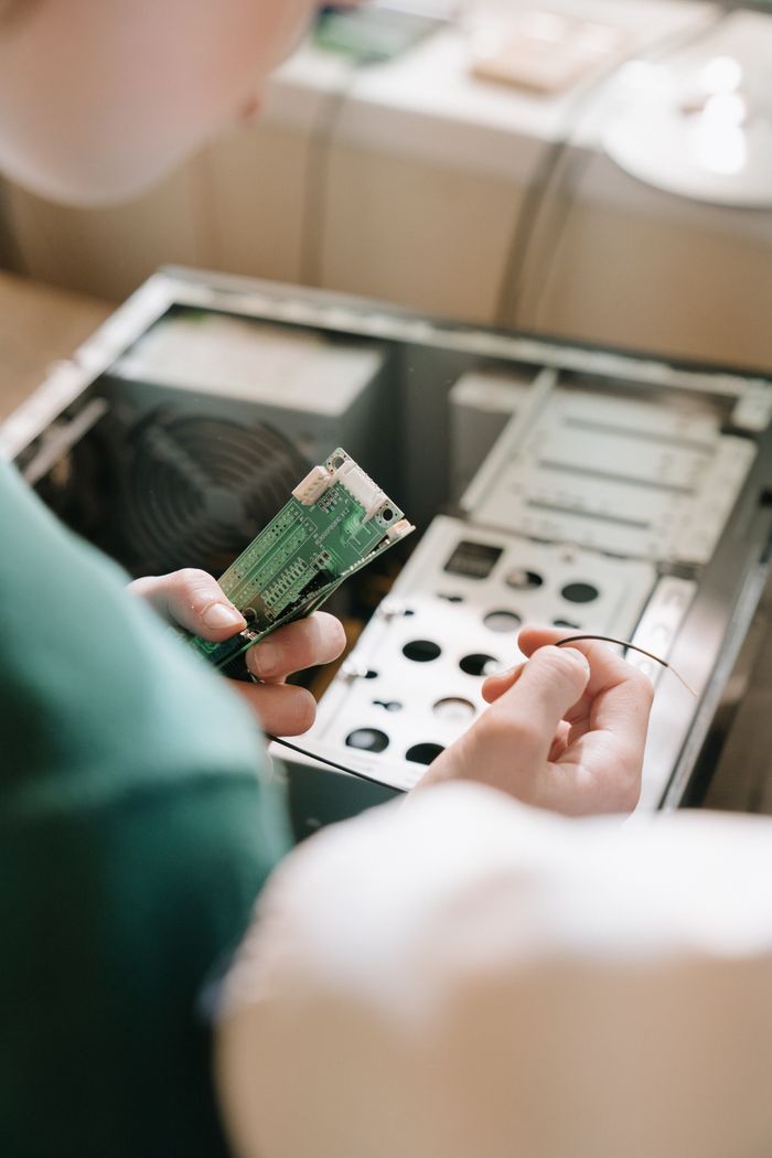 Close-up of hands installing RAM into an open PC case, depicting computer repair and maintenance.
